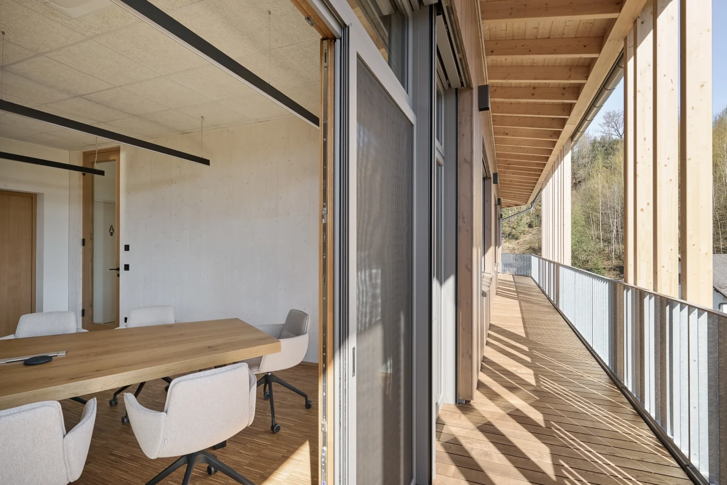 Überdachter Balkon des Bürohauses Riebenbauer mit vertikalen Holzlamellen als Sonnenschutz