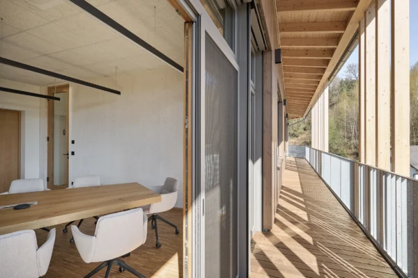 Überdachter Balkon des Bürohauses Riebenbauer mit vertikalen Holzlamellen als Sonnenschutz