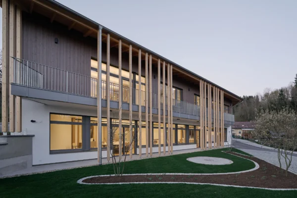 Abendansicht des Bürohauses Riebenbauer mit rhythmischer Holzlamellenfassade und großzügigen Fensterflächen