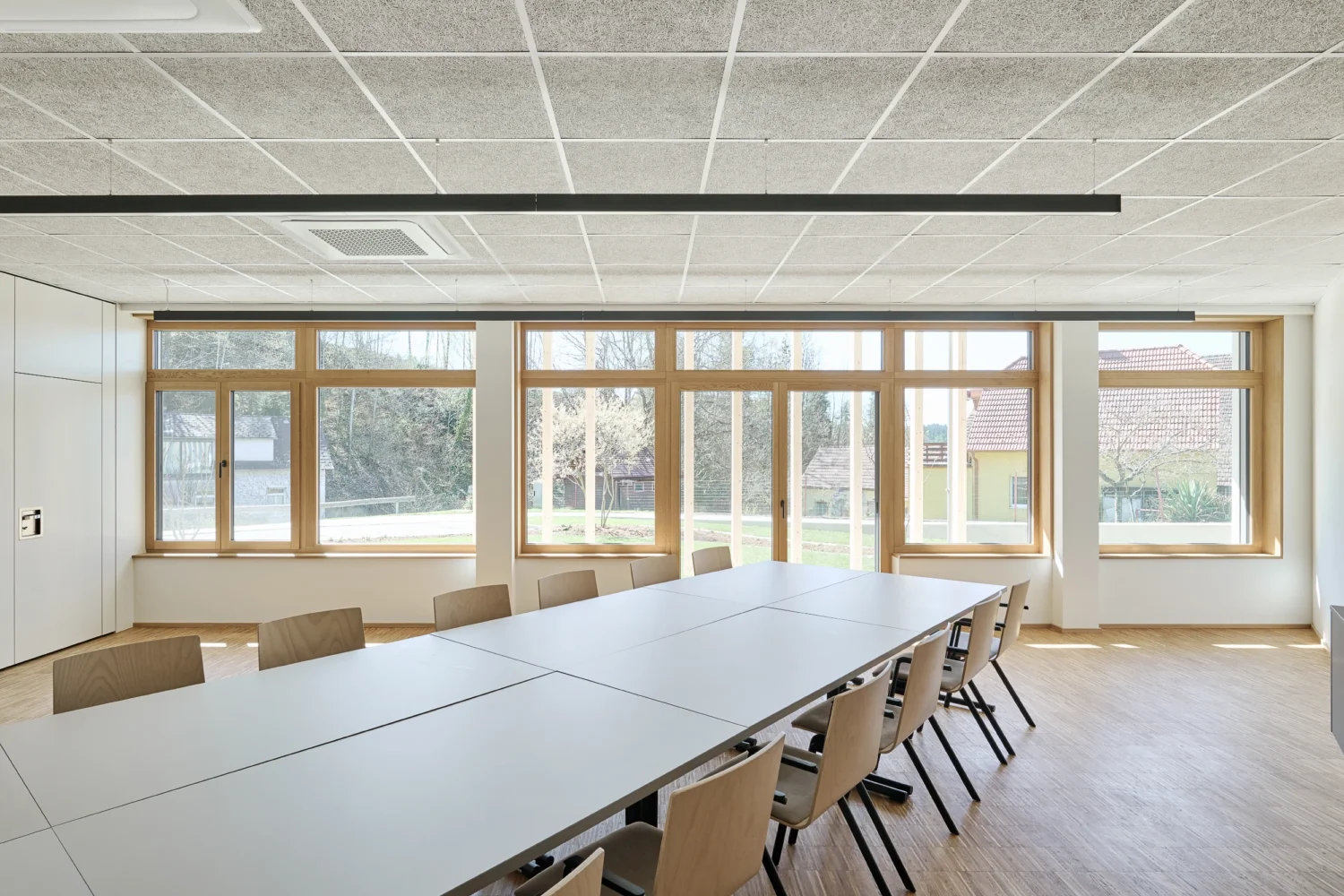 Heller Besprechungs- und Veranstaltungsraum im Bürohaus Riebenbauer mit Holzfenstern und Blick ins Freie